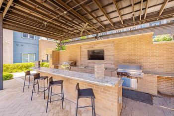 A brick patio with a barbecue grill and four chairs. at Bridge at Henley, Texas